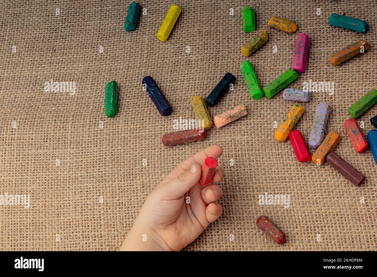 Used color crayons and a toddlers hand holding one Stock Photo Alamy