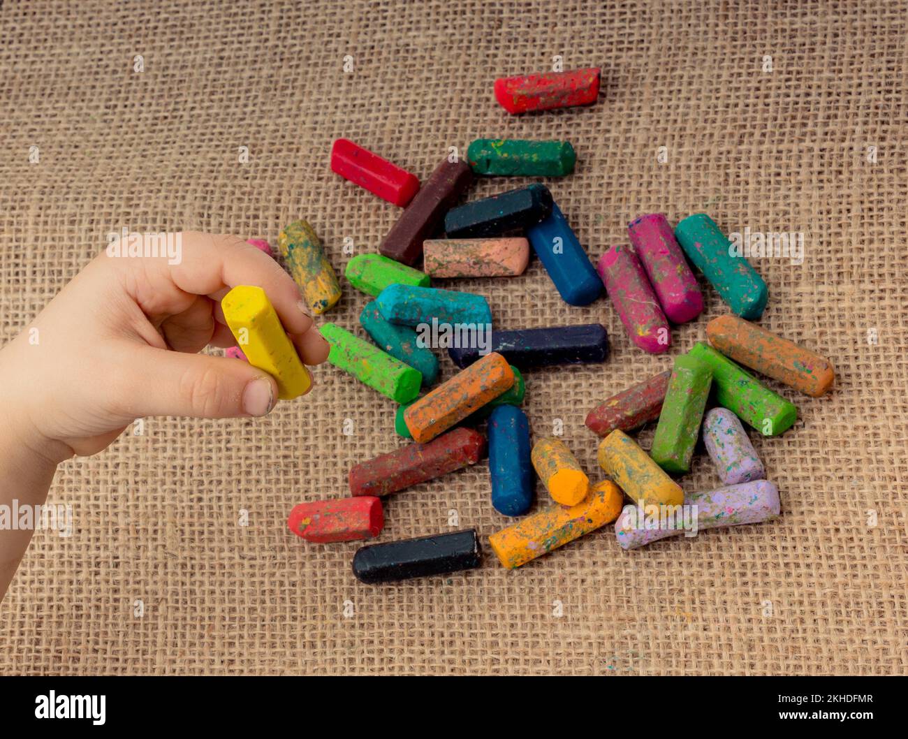 Used color crayons and a toddlers hand holding one Stock Photo Alamy
