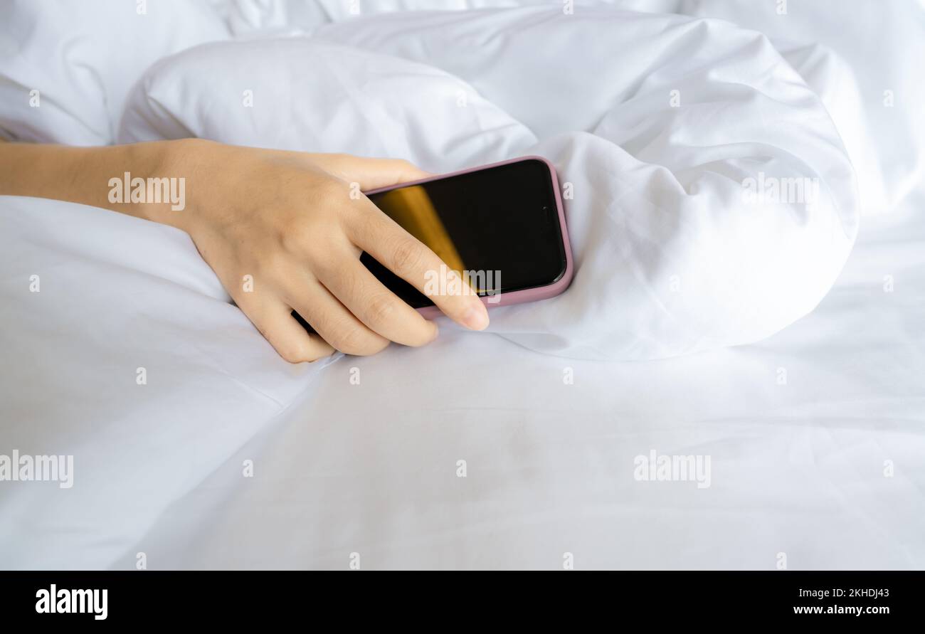 Woman sleeping in bed and hand holding mobile phone. Woman using
