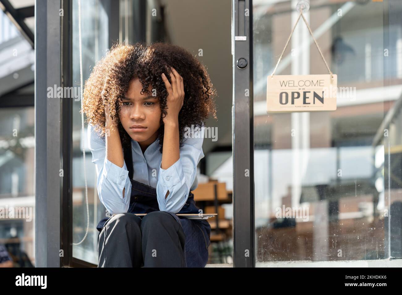 black woman waiter of street cafe is waiting for clients, customersm she is bored, no people in their cafe. small business owner. Stock Photo