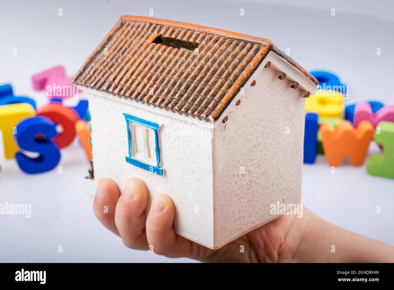 Model house in hand with colorful alphabet letters behind Stock Photo