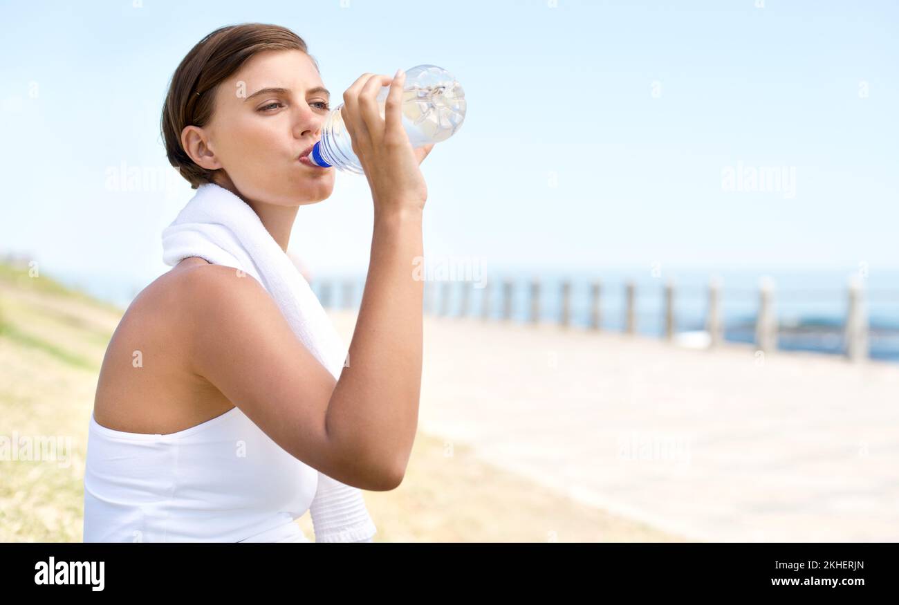 Happy and hydrated. a beautiful woman drinking bottled water during a