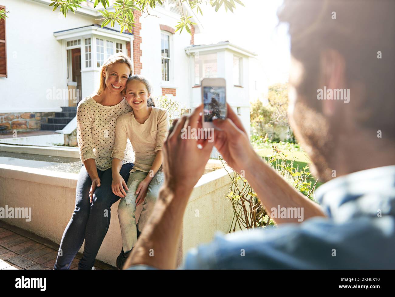 Its the little moments that make life big. A man using his smartphone to take a photo of his family sitting outdoors. Stock Photo