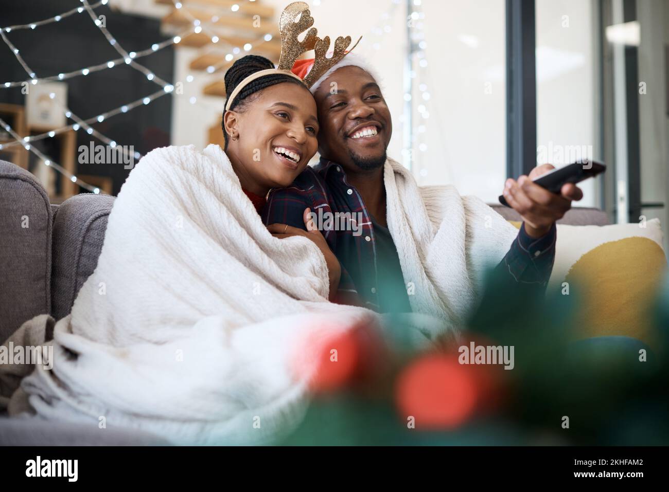 Christmas, comfort and African couple watching tv, news or a movie from the living room sofa. Television, relax and black man and woman on the couch Stock Photo
