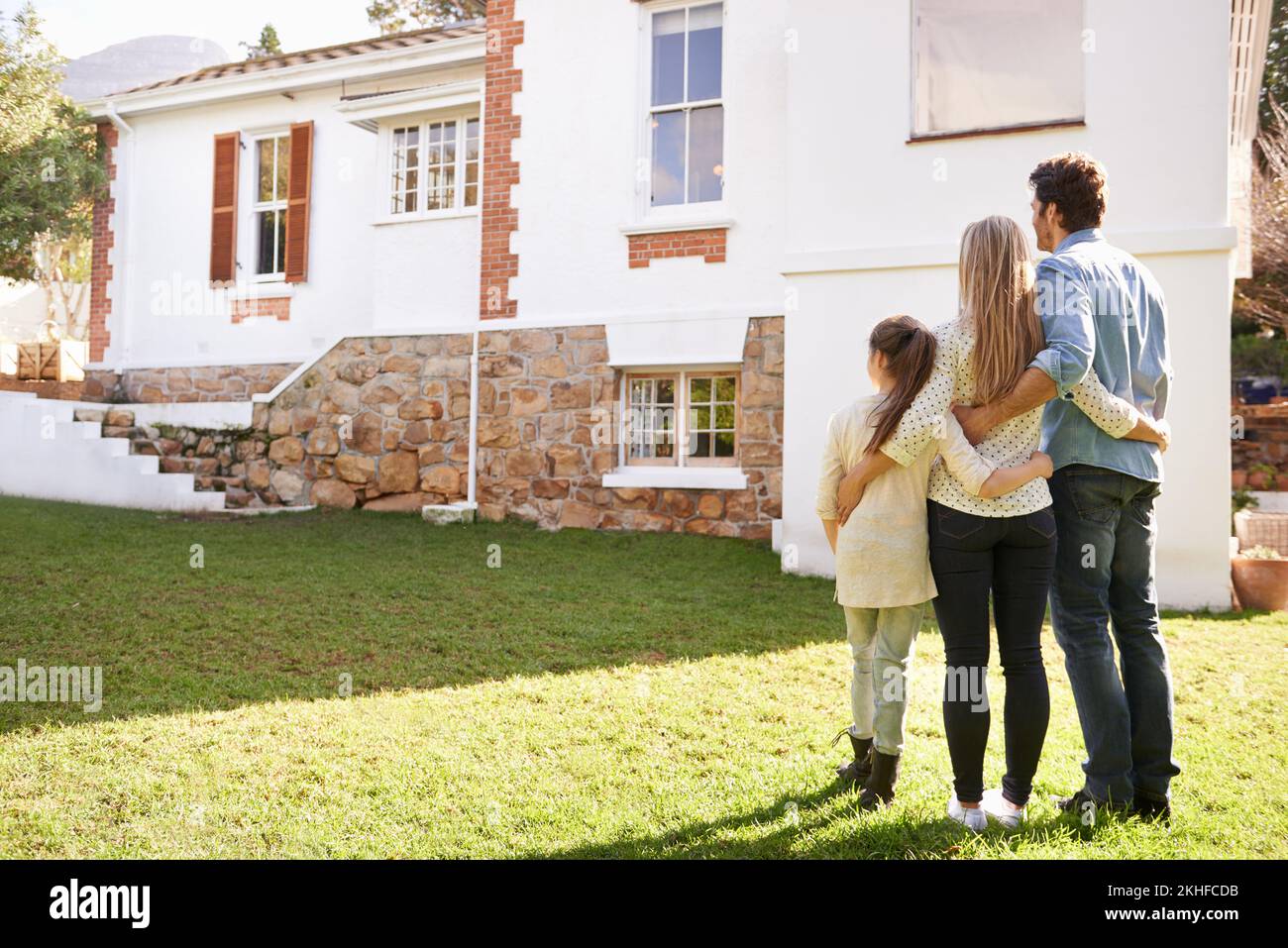 Not just a house, but a home. A family standing outdoors admiring their new home. Stock Photo