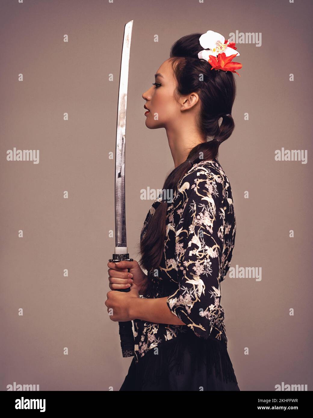 Deadly and beautiful. Studio shot of an attractive young woman holding a samurai sword. Stock Photo