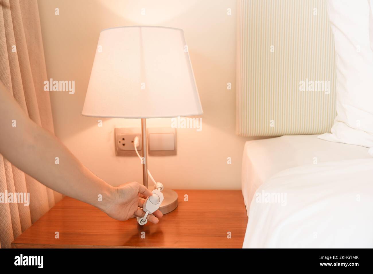 Woman hand turning on or turning off switch the minimal lamp in modern bedroom. Apartment living concept Stock Photo