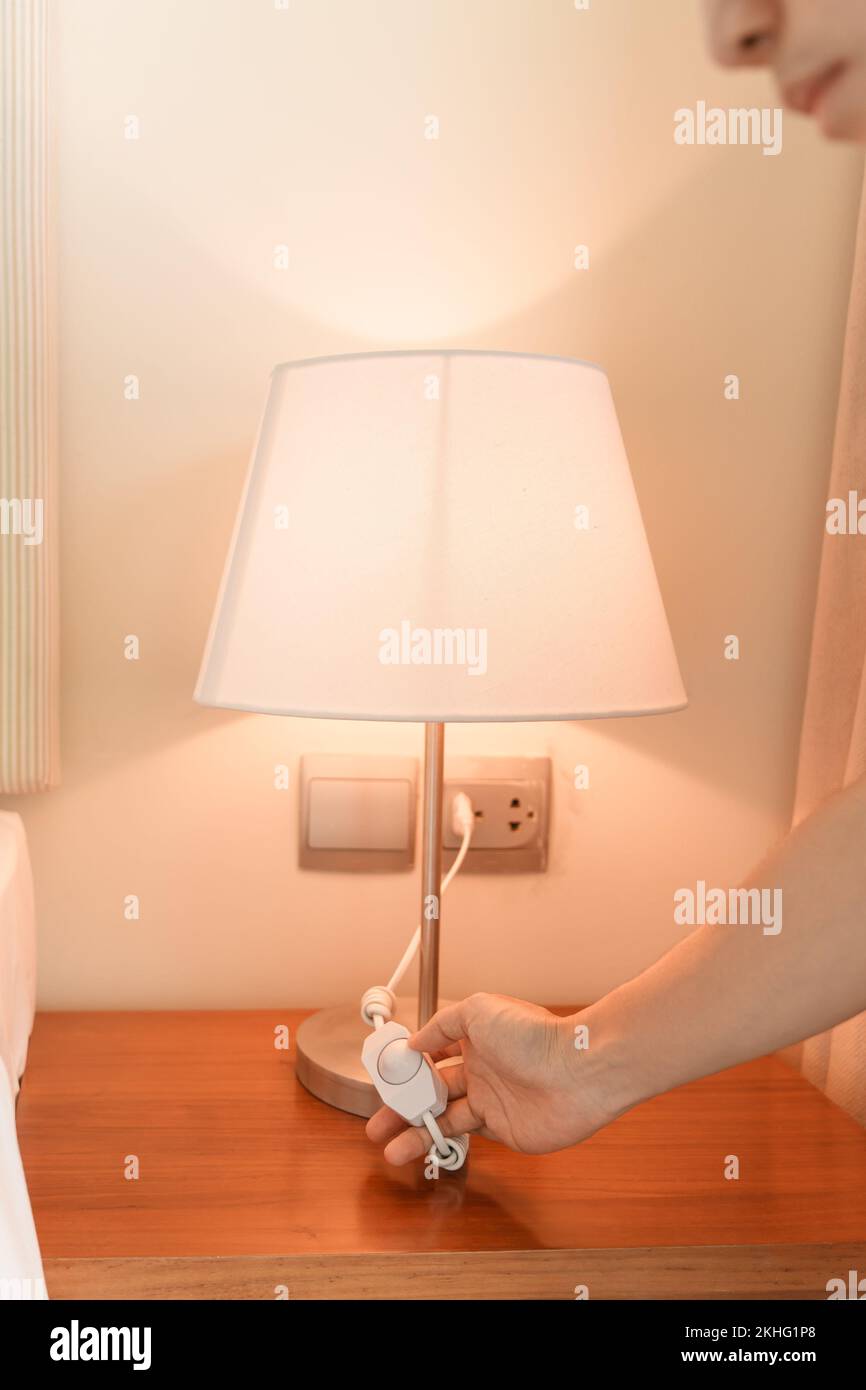 Woman hand turning on or turning off switch the minimal lamp in modern bedroom. Apartment living concept Stock Photo
