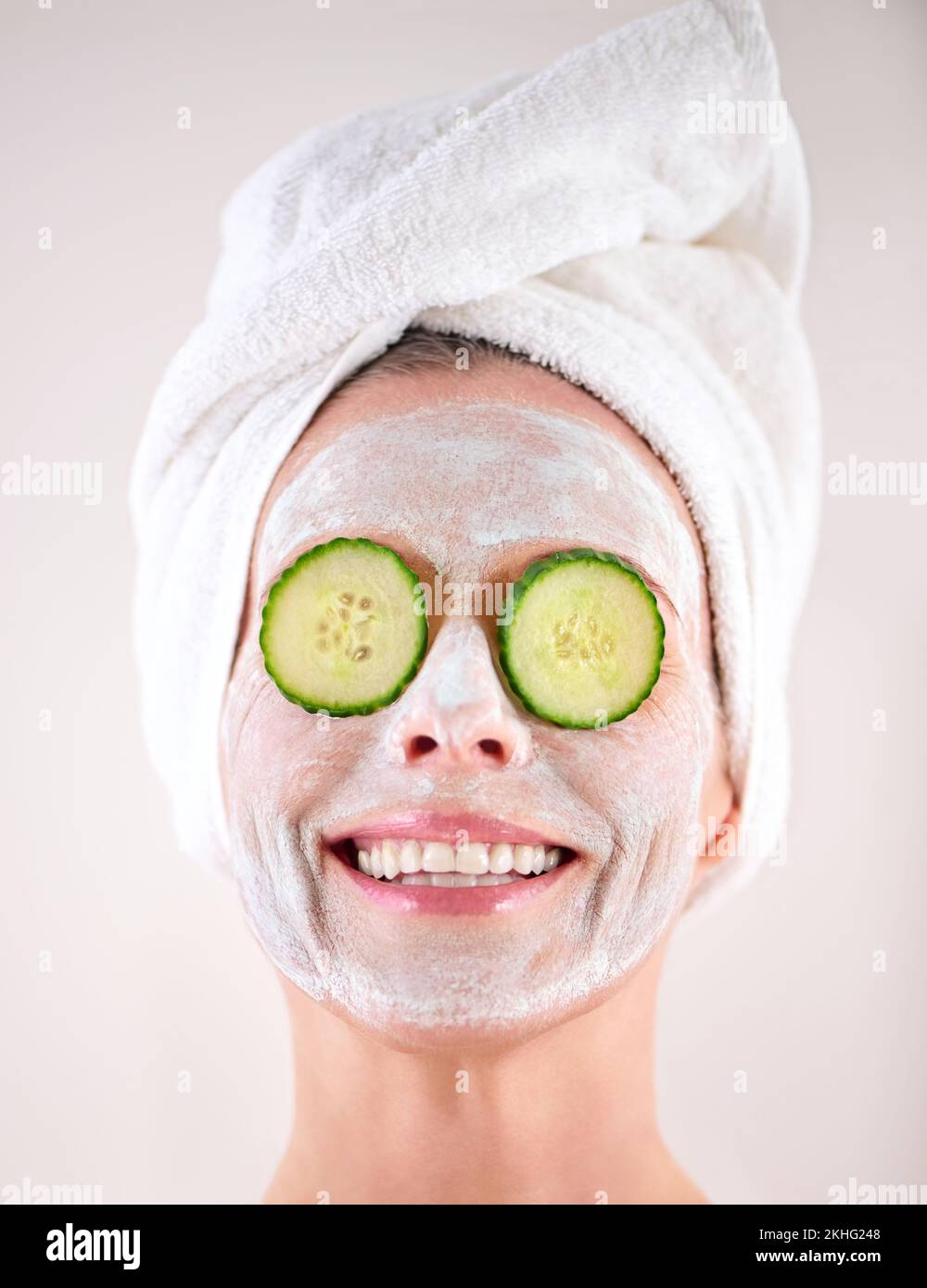 Make your skin happy. a mature woman with a mask applied to her face and cucumber slices on her eyes. Stock Photo