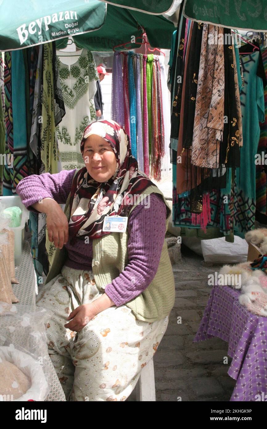 Street scene, woman dressed in traditional Turkish dress serving at dress stall on main shopping street, Beypazari, Turkey Stock Photo