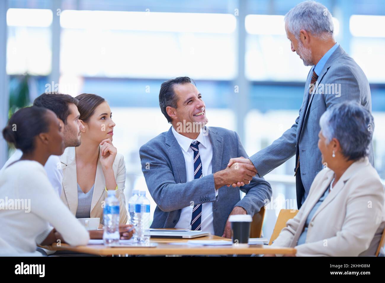 Were looking forward to working with you. A cropped shot of two businesspeople shaking hands at a meeting with colleagues. Stock Photo