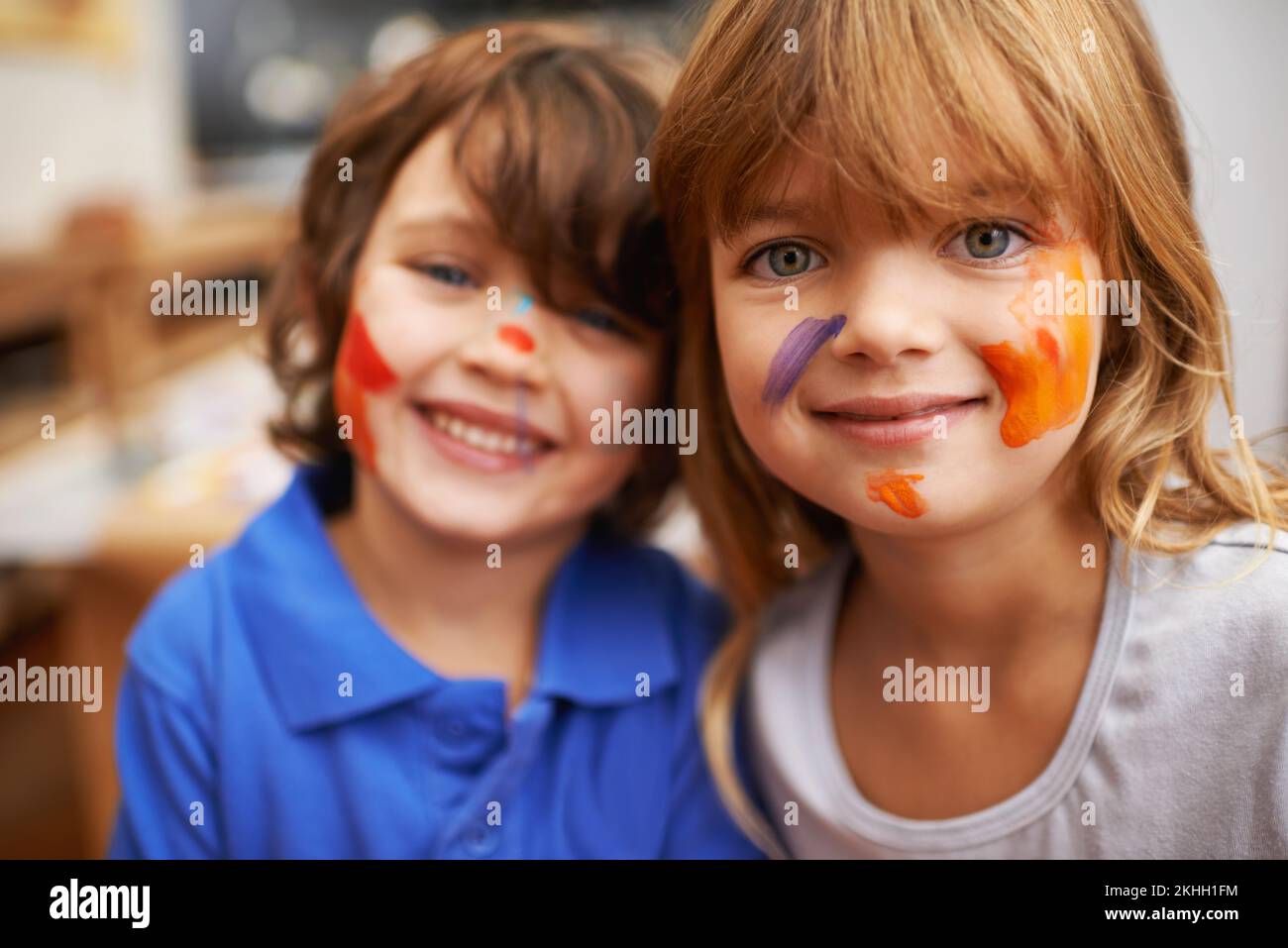 Being an artist is messy business. A portrait of two cute young siblings with faces full of paint. Stock Photo