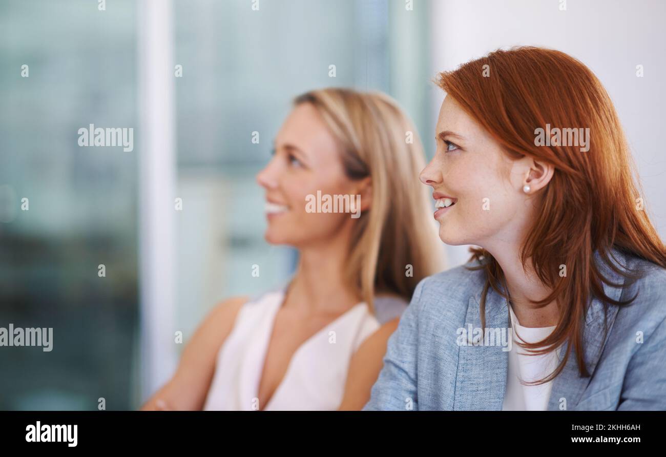 Listening to a charismatic colleague. two colleagues looking impressed by a colleague. Stock Photo
