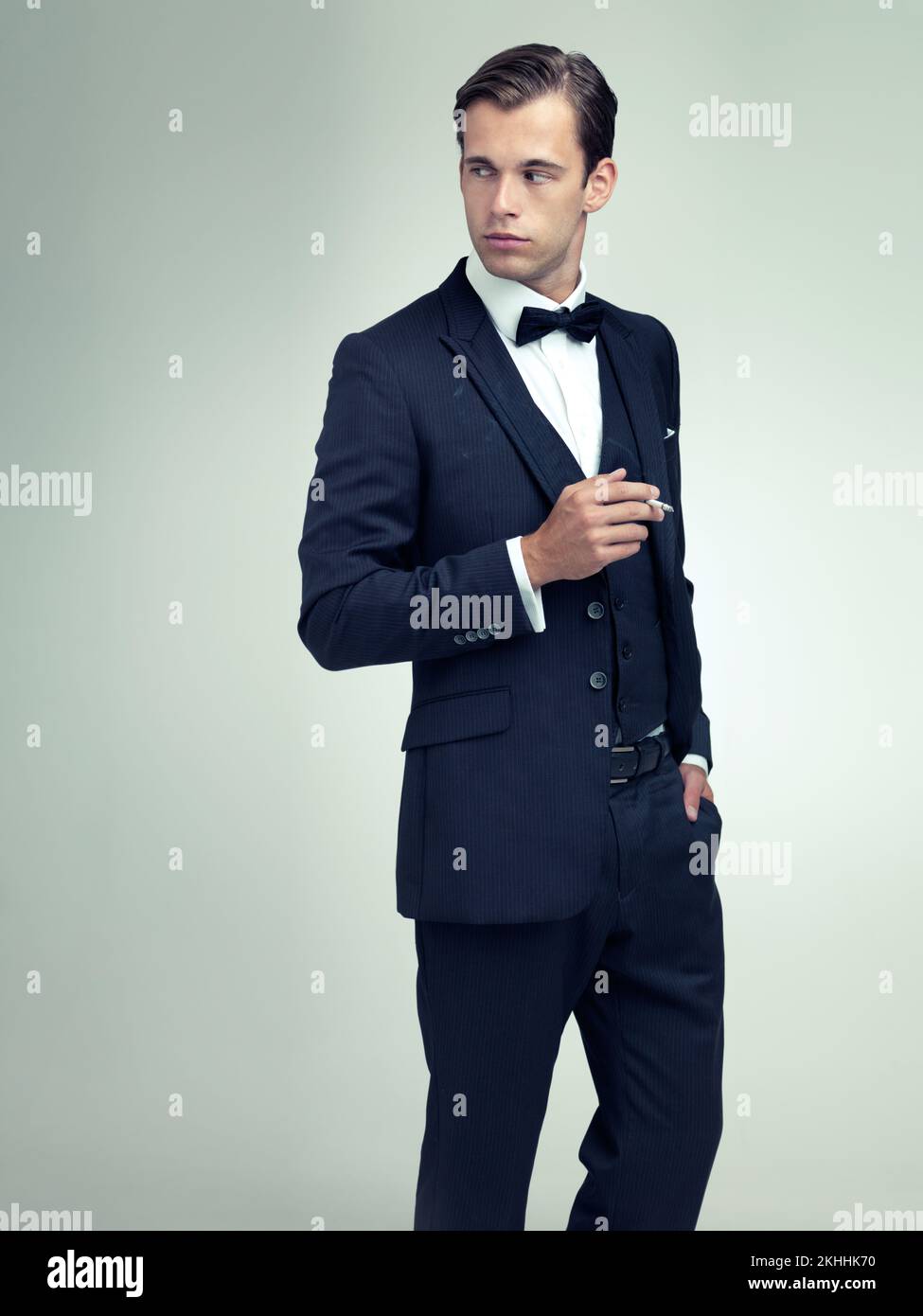 Clothes dont make the man, but they can make the man look great. A studio shot of a dapper young gentleman smoking a cigarette. Stock Photo