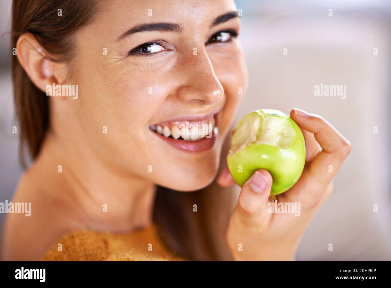 An apple a day keeps the doctor away. An attractive young woman biting into a green apple. Stock Photo