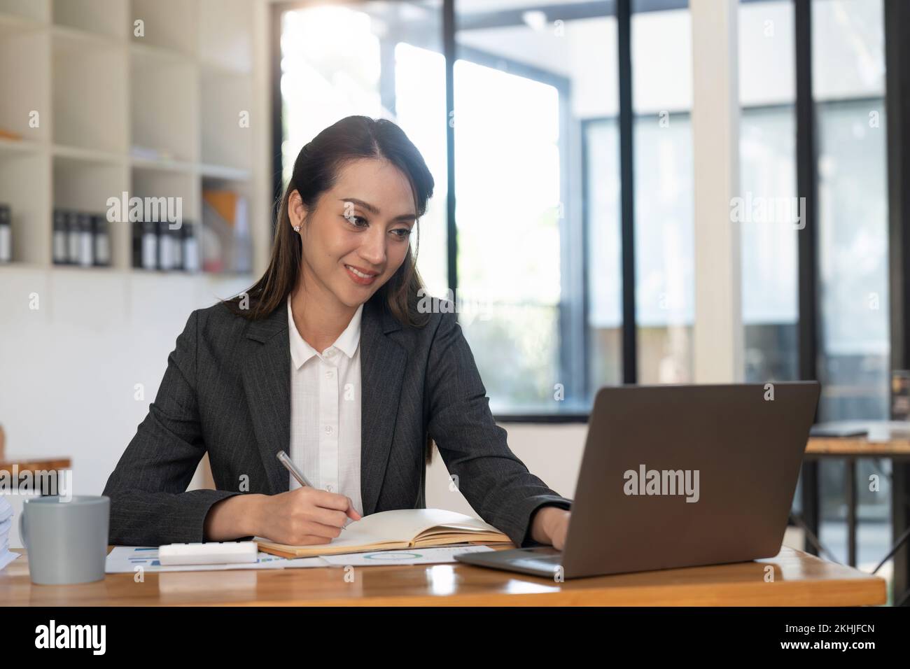 Asian accountant using calculator while taking notes on office desk. Stock Photo