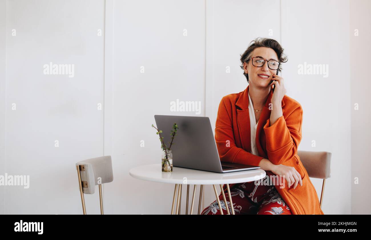 Mature business woman making a phone call while working remotely. Mature businesswoman making contact with one of her clients while working in a cafe. Stock Photo