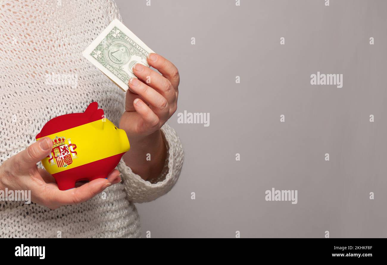 Flag of Spain on money bank in Spanish woman hands. Dotations, pension fund, poverty, wealth