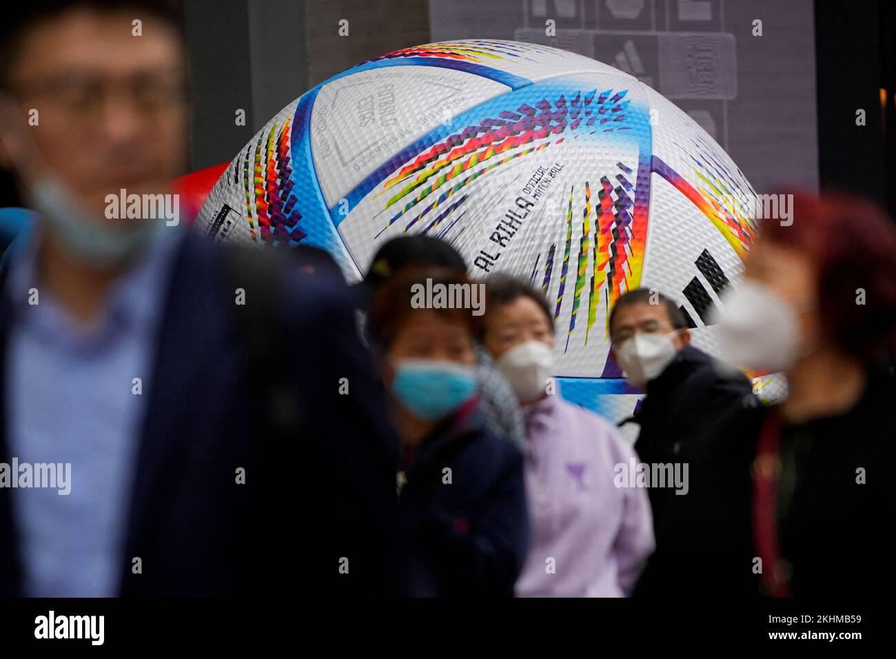 People wearing face masks walk by the giant model of FIFA World Cup Qatar 2022 match ball, amid the coronavirus disease (COVID-19) outbreak in Shanghai, China, November 23, 2022. REUTERS/Aly Song Stock Photo