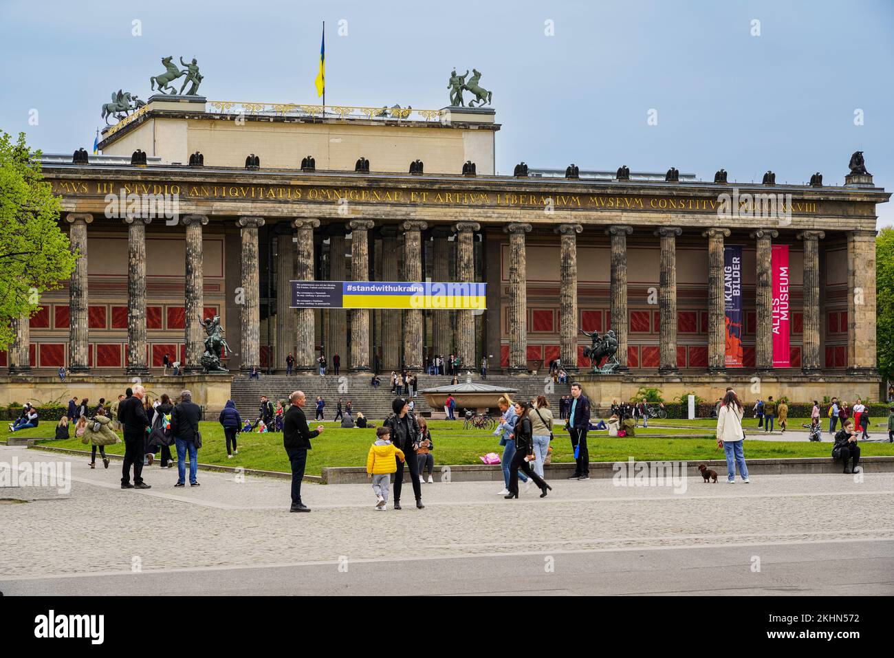 People in front of the Old Museum in Berlin. A banner with the inscription Stand With Ukraine hangs on the building. Stock Photo