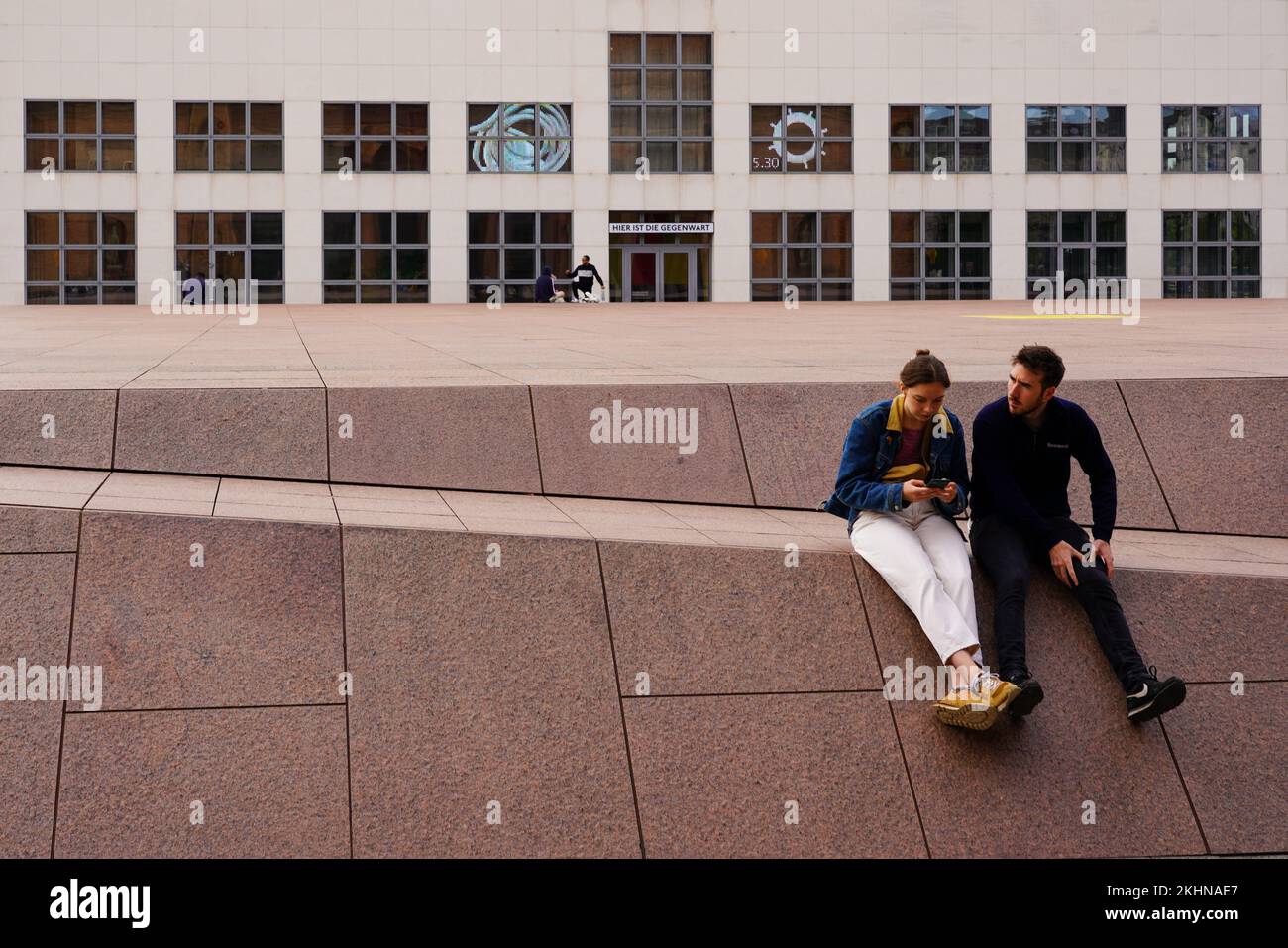 A couple sitting in front of the Alte Kunsthalle overlooking the cube-shaped building of the Galerie der Gegenwart (Gallery of the Present). Stock Photo