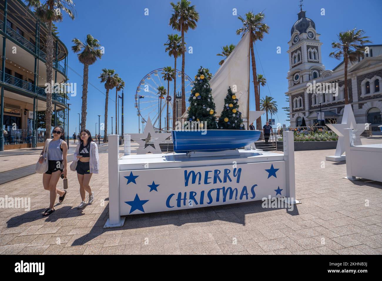 Adelaide, Australia. 24 November 2022.  People walk past a Merry Christmas  sign in the coastal resort of Glenelg, Adelaide  on a warm sunny day ahead of the Glenelg Christmas Pageant Credit: amer ghazzal/Alamy Live News Stock Photo