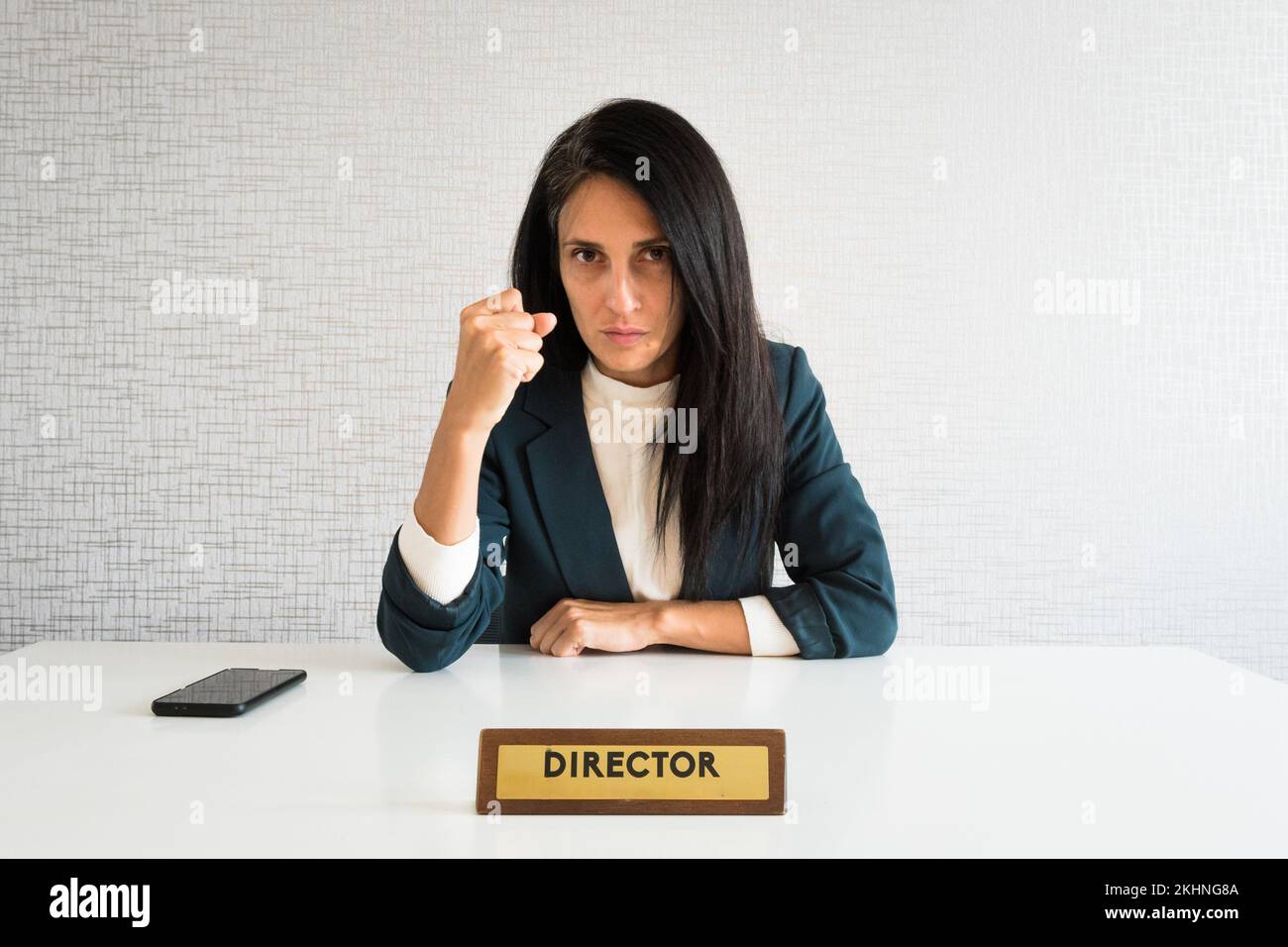 Young cute caucasian brunette business woman director in office show fist to camera at work for employee resentful angry serious look at camera. POV e Stock Photo