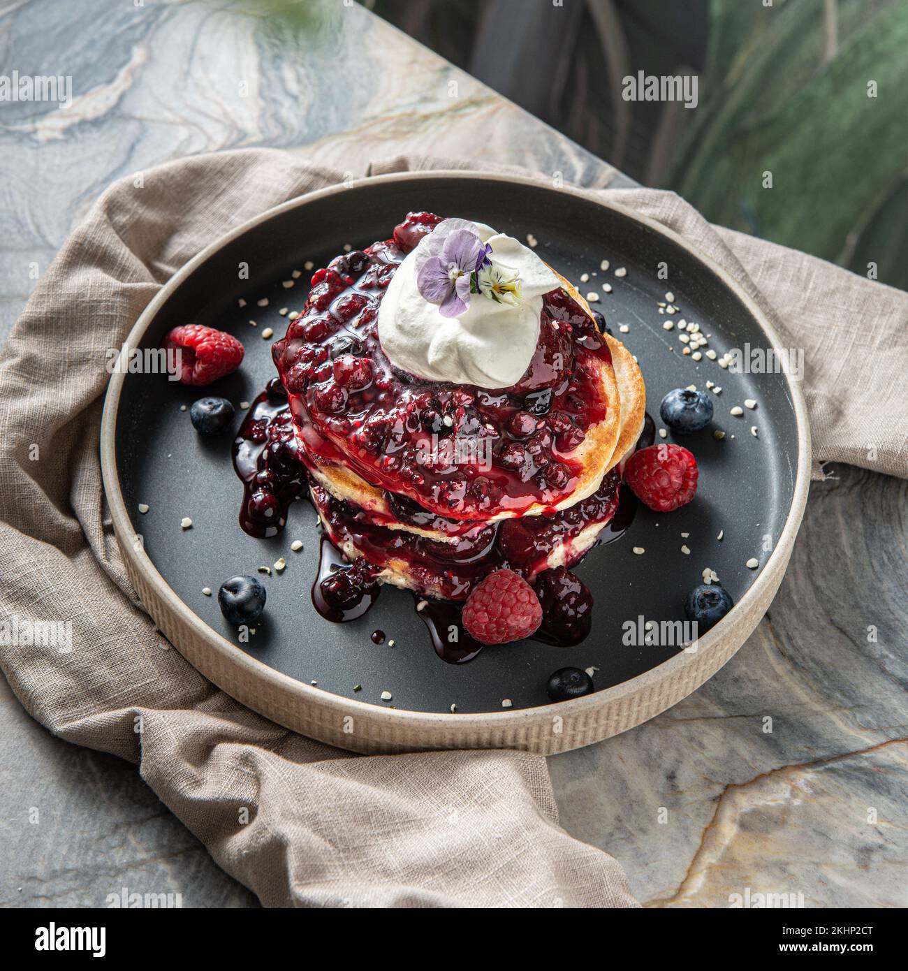 A top view of a raspberry and blueberry pancake with cream on top ...