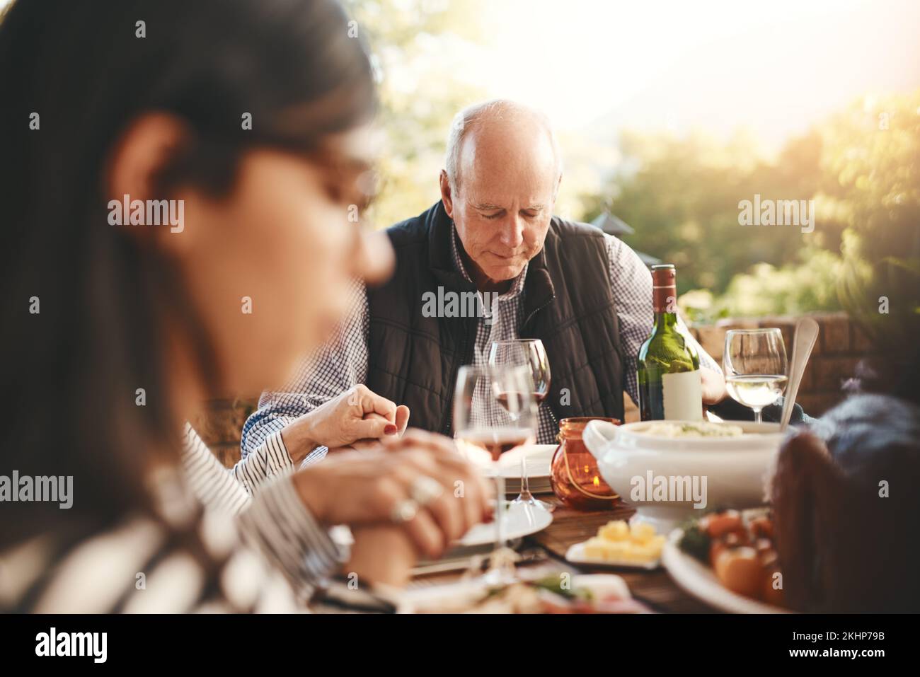 Family party, celebration and praying before a lunch, Christmas and gathering with food in a backyard. Holding hands, gratitude and friends with a Stock Photo