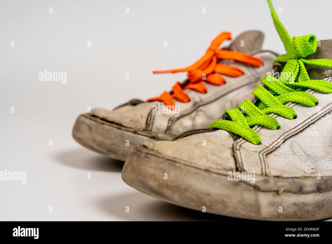 worn old torn white sneakers with colored laces on a white background ...