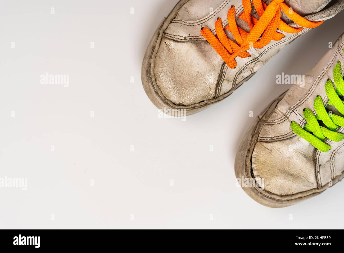 worn old torn white sneakers with colored laces on a white background ...