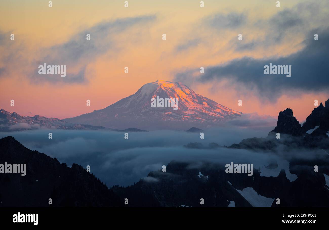 A beautiful scenery of the snowy peak of the Mount Adams during sunset with clouds in the foreground Stock Photo