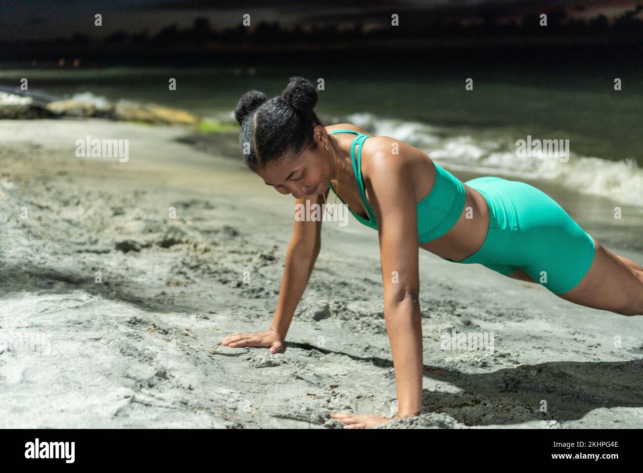 Afro woman doing push-ups on the beach Stock Photo
