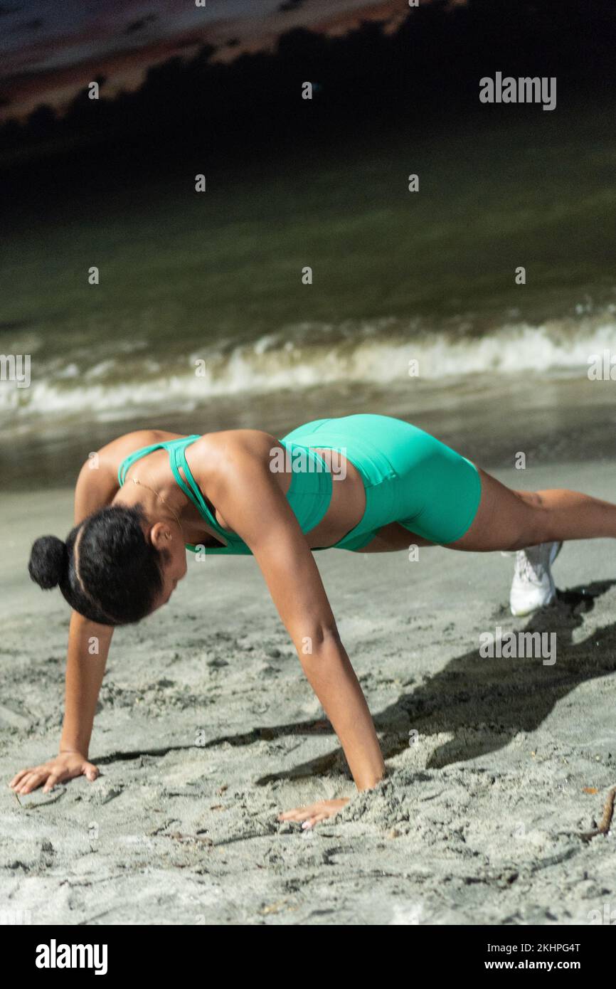 Young woman doing push-ups on the beach Stock Photo