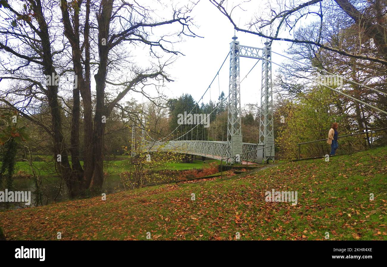 A 2022 view of  Penkiln Suspension Bridge, Minnigaff  (Dumfries  and Galloway, Scotland) also known as King George V Suspension Bridge, Newton Stewart D & G. Minnigaff. Built 1911 by D H and F Reid, Victoria Works, Ayr, engineers. A light lattice-girder span supported from wire-rope cables by iron-rod suspenders. The pylons are also of lattice construction.   The river  forms the boundary between the parishes of Minnigaff and Penninghame. It was erected on the  22/6/1911 and is built from cast and wrought iron. Major structural repairs 1982 by Craich and Hogg, engineers; W & J Barr contractors Stock Photo