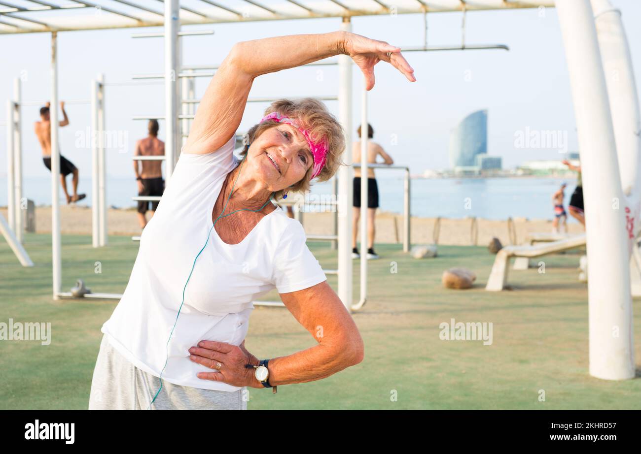 Old woman doing fitness exercises outdoors Stock Photo