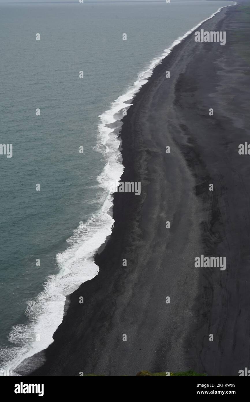 The ocean with white foamy waves splashing into the black beach Stock ...