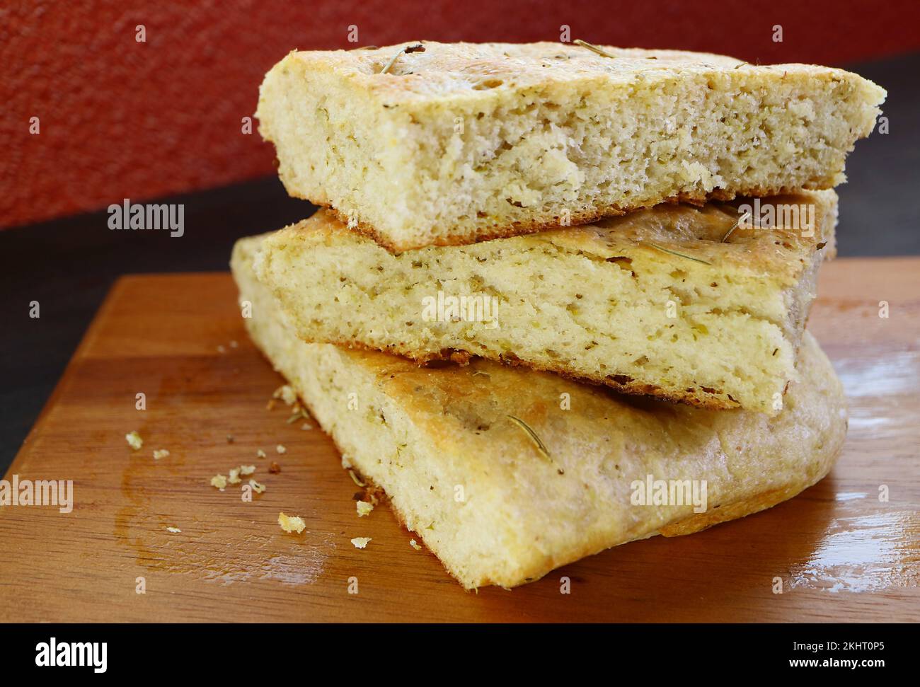 Closeup Mouthwatering Rosemary Focaccia Bread Slices Piled Up on Wooden Breadboard Stock Photo