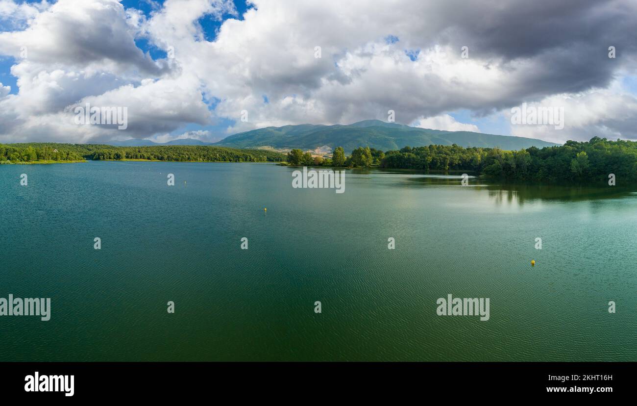 Lake covered with vegetation against backdrop of Rhodope mountains and clouds. Panorama, top view Stock Photo