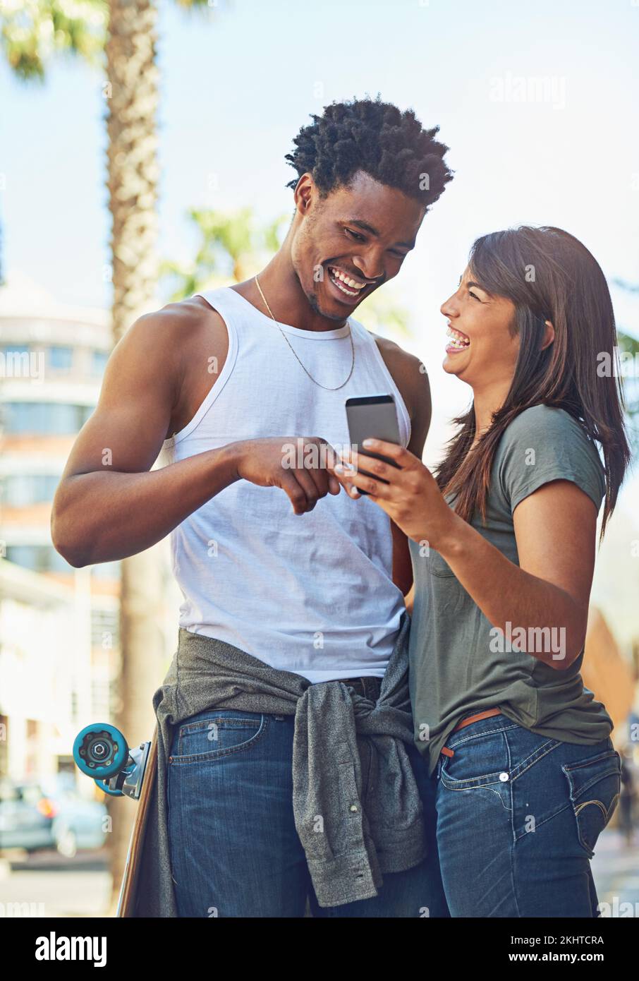 Happy, smile and couple on a phone in city watching a comic, comedy or funny video on social media. Happiness, love and interracial man and woman Stock Photo