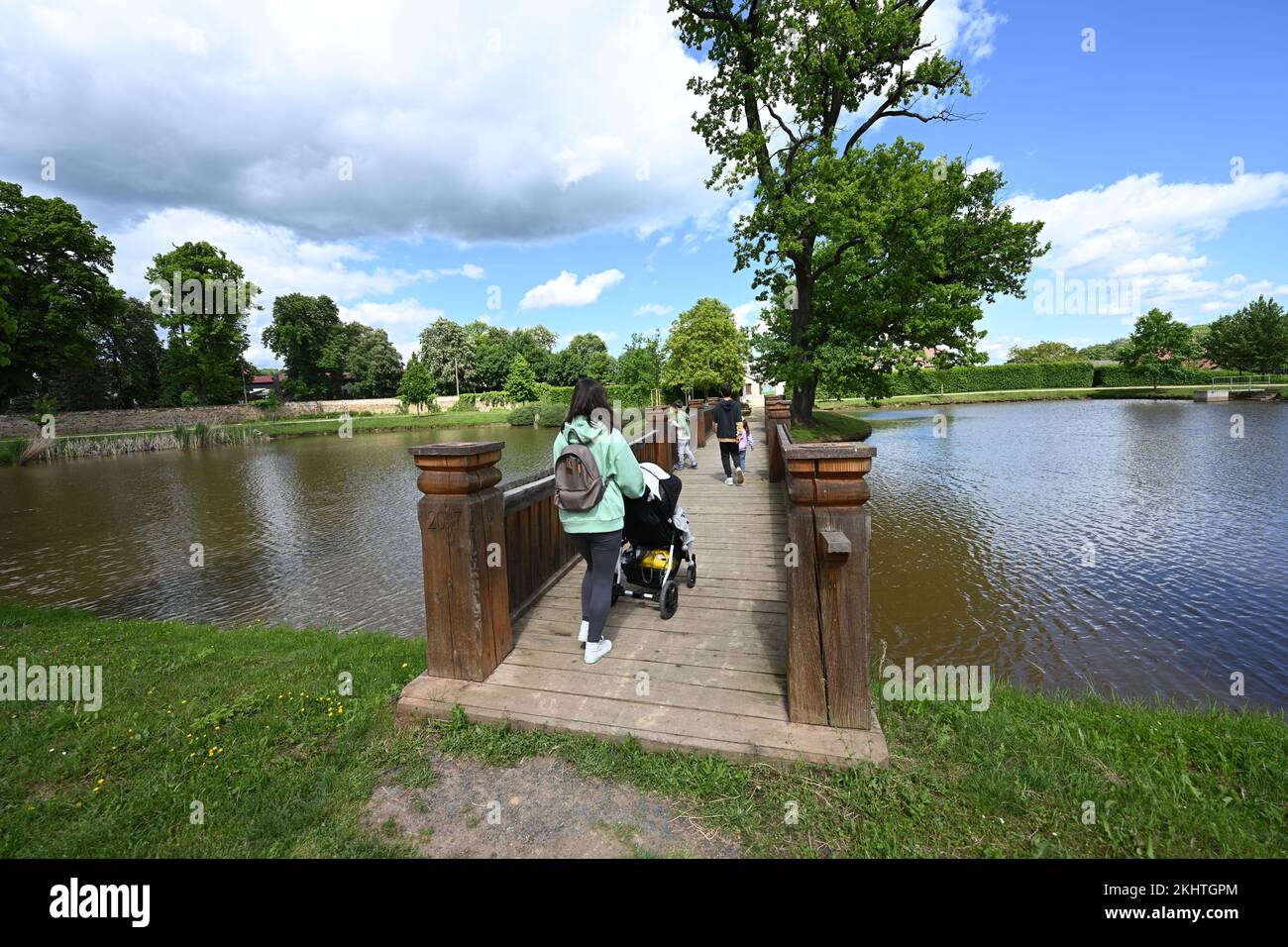 Mother with kids walking at wooden bridge on pond in Panska Garden,  Kunstat in Moravia, Czech Republic. Stock Photo