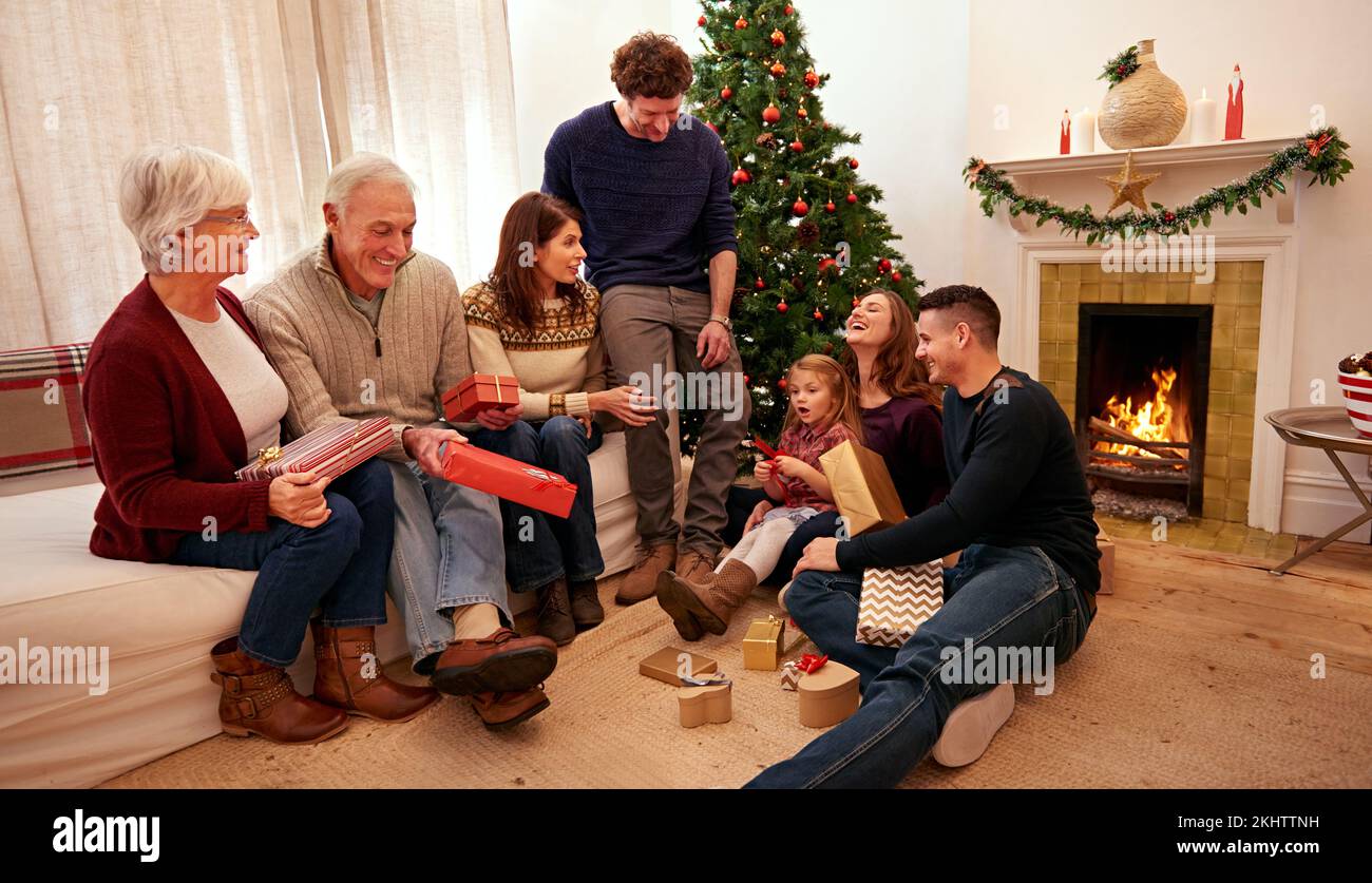 Big family, christmas and gift in home living room for celebration, happiness and bonding together. Happy family, grandparents and children with Stock Photo