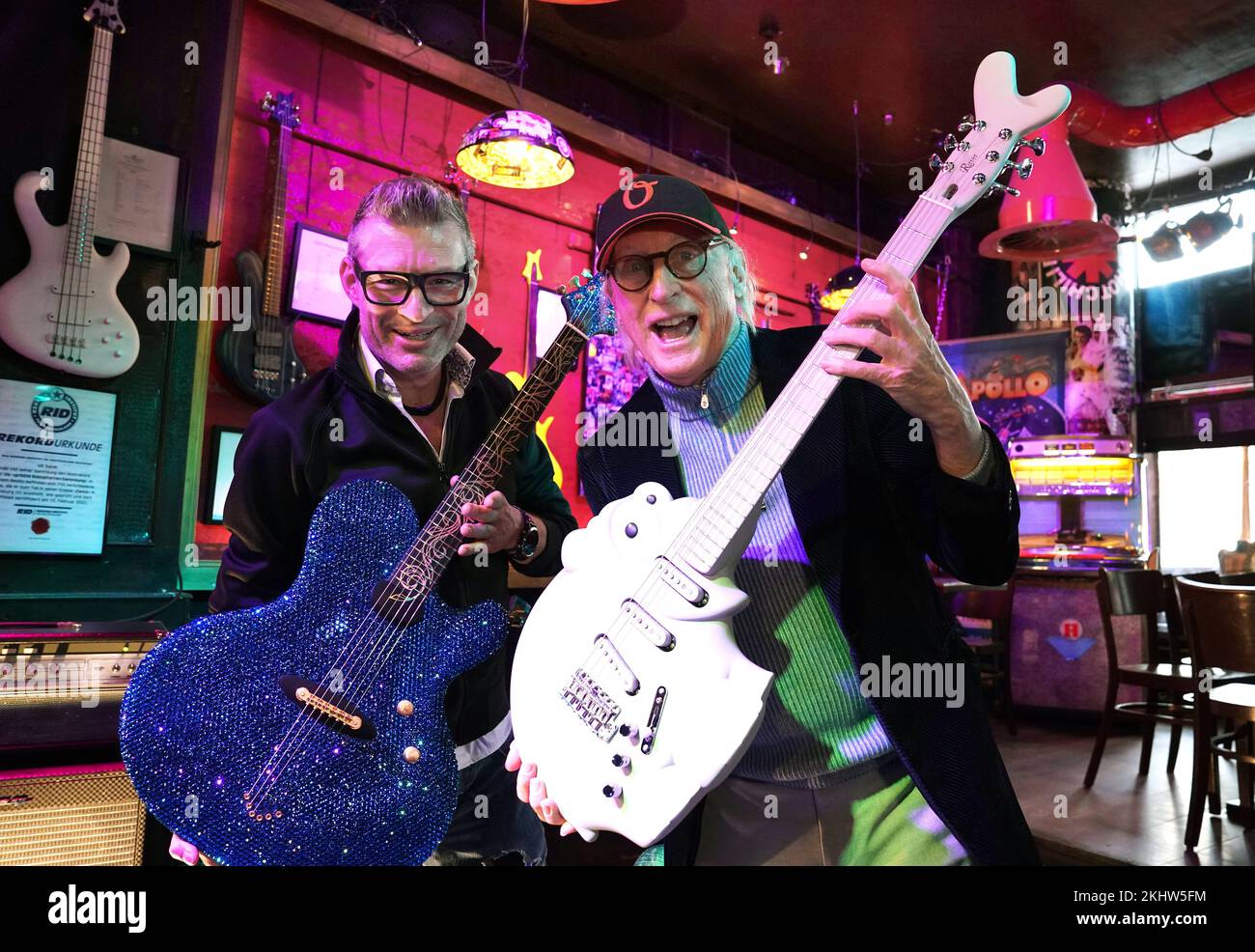 24 November 2022, Hamburg: Guitar maker Jens Ritter (l) holds up the "25th  Anniversary of Magic & Freedom" guitar, studded with more than 11,000  Swarovski stones, and Otto Waalkes the Ottifanten guitar