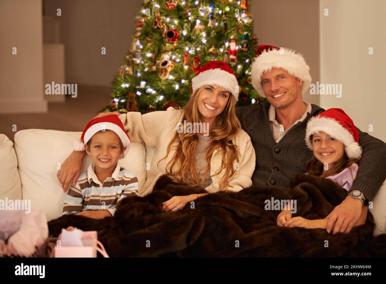 Happy family at Christmas, couple and children on sofa in living room with christmas tree, smile and happiness. Portrait of mother, father and Stock Photo