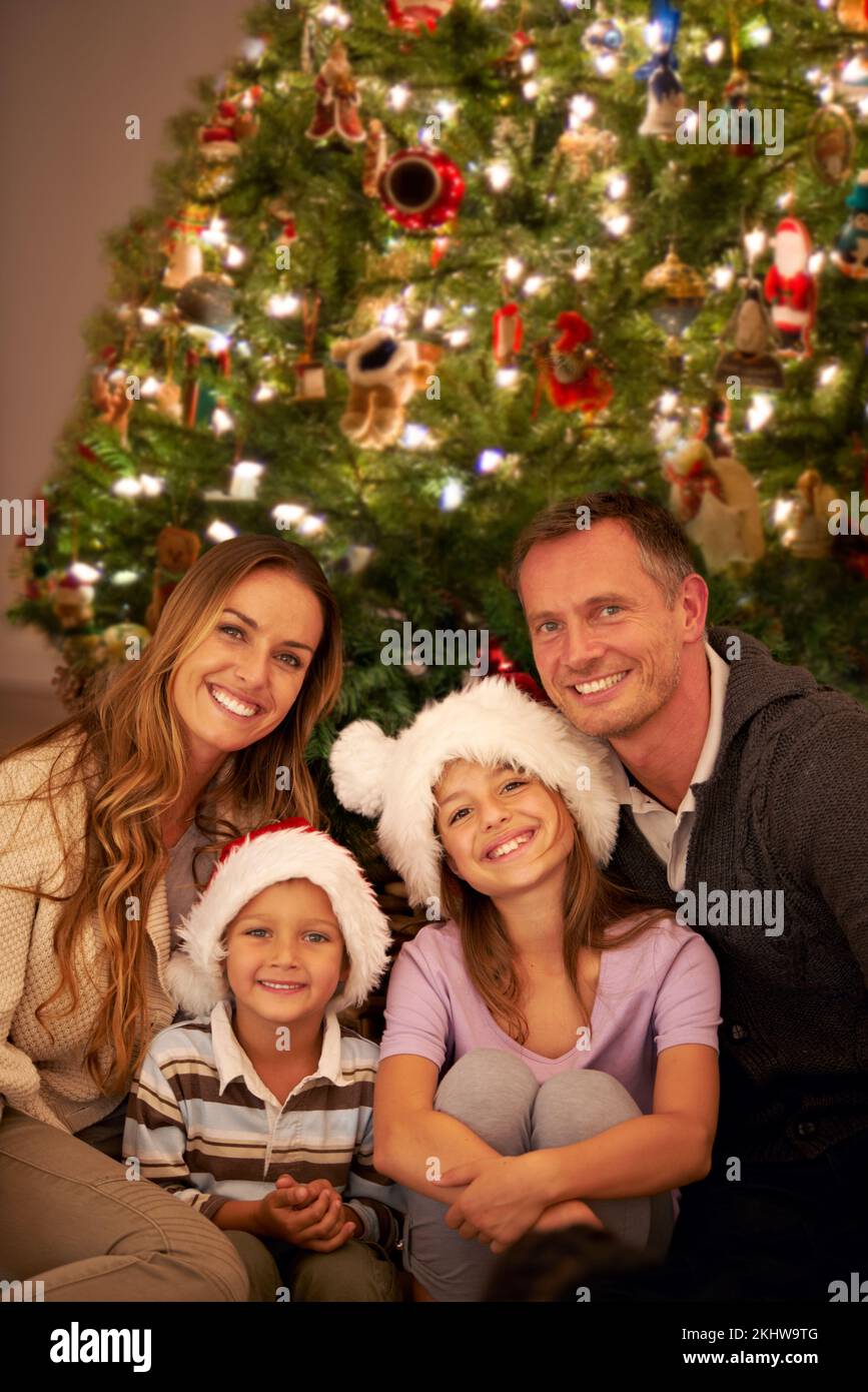 Portrait, happy family and christmas tree in living room, smile and celebrate for love or happiness. Mother, father and young children or smiling at Stock Photo