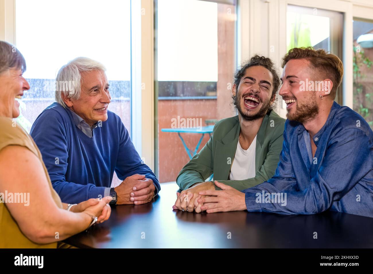 happy family welcomeing the son’s new boyfriend, inclusion, tollerance and coming out from the closet concept, focun on father looking his son laughin Stock Photo