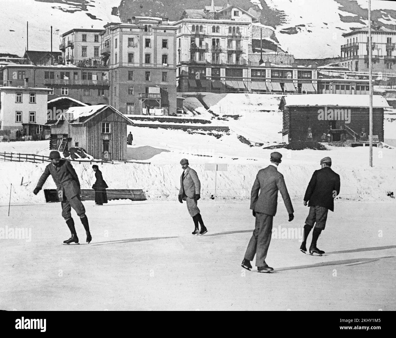 An early 20th century black and white photograph showing a group of men skating on ice in the town of St. Moritz in the Swiss Alps. Stock Photo