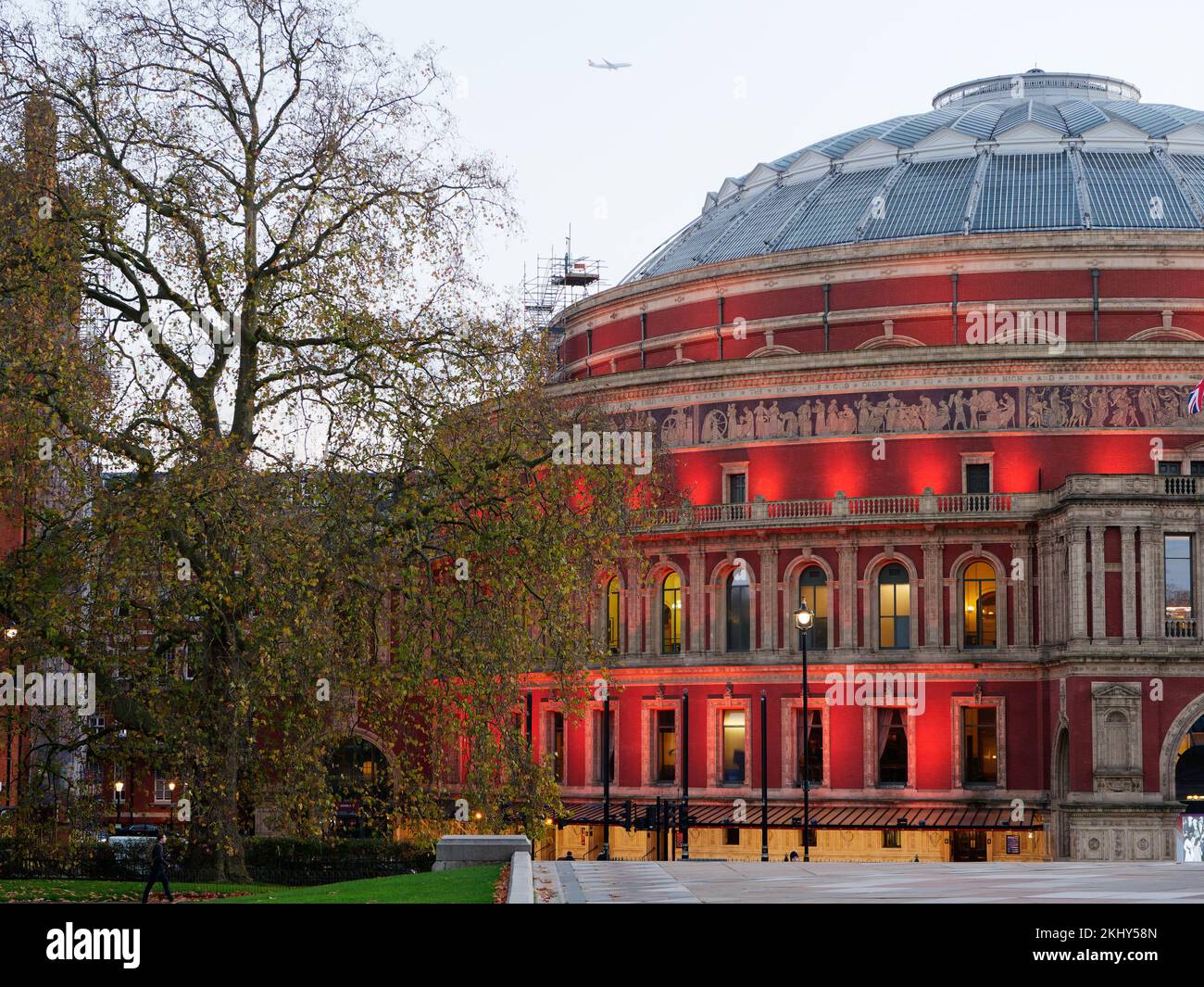 Royal Albert Hall exterior floodlit on a atumn evening as a plane flies overhead. Stock Photo