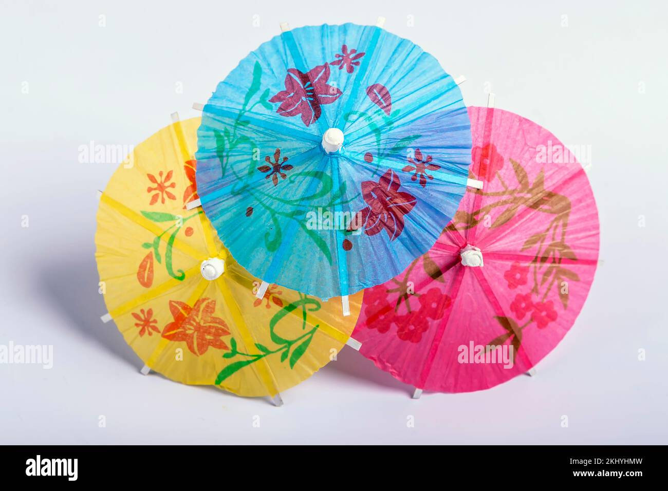 Three decorative paper umbrellas of three different colors against a white background Stock Photo