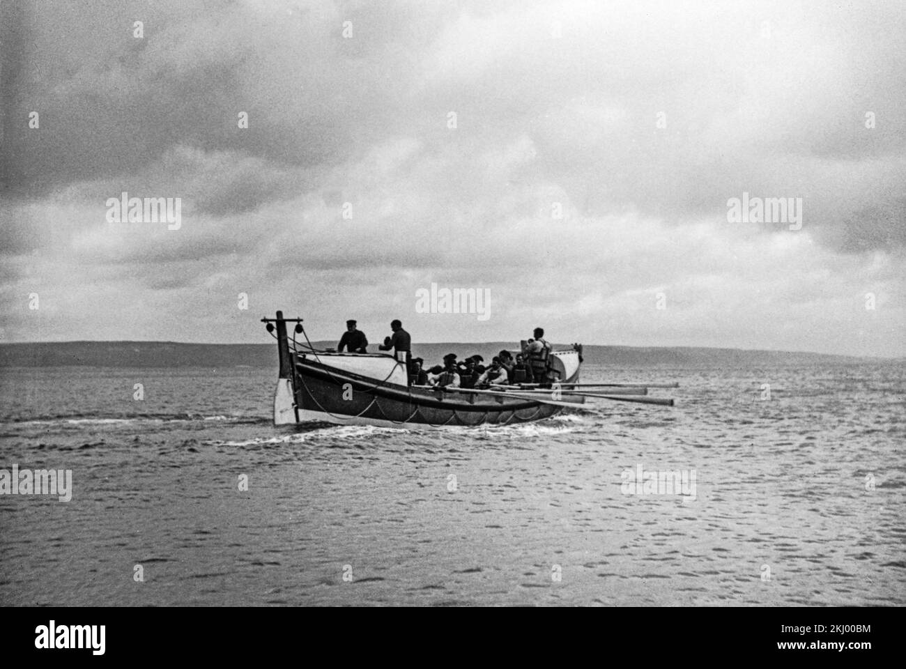 A late 19th or early 20th century black and white photograph showing a Life Boat being rowed by member of the  Royal National Lifeboat Institution, on coastal waters in England. Stock Photo